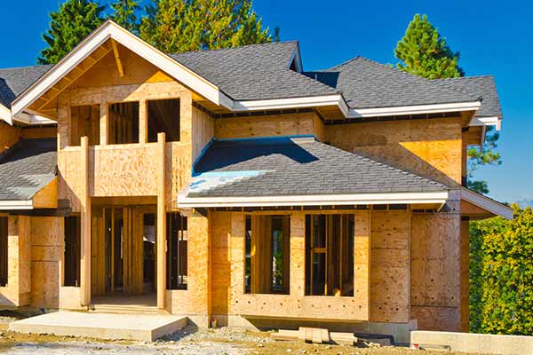 Newly constructed home getting new gray shingles installed