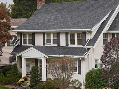 Front view of a mid-class, two-story white home with gray GAF shingles on its roof